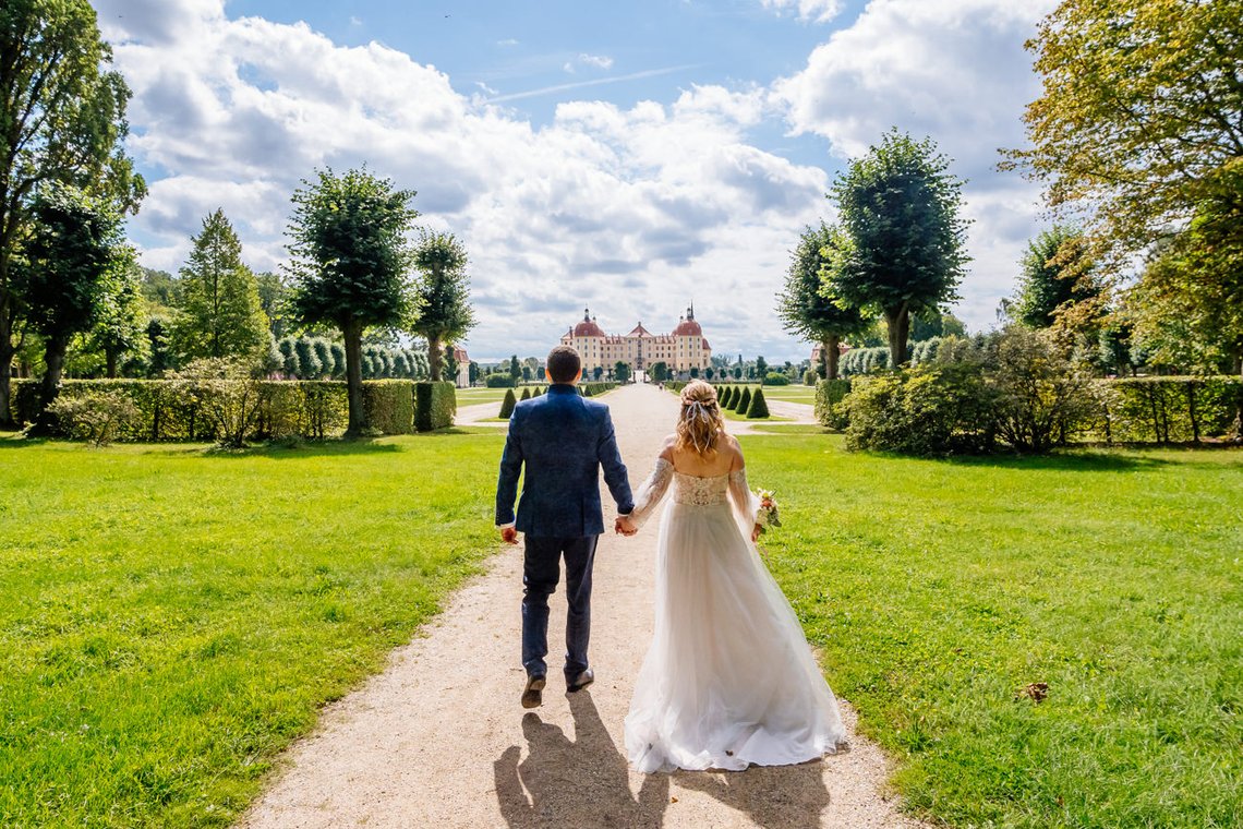 Brautpaar läuft auf das Schloss Moritzburg zu